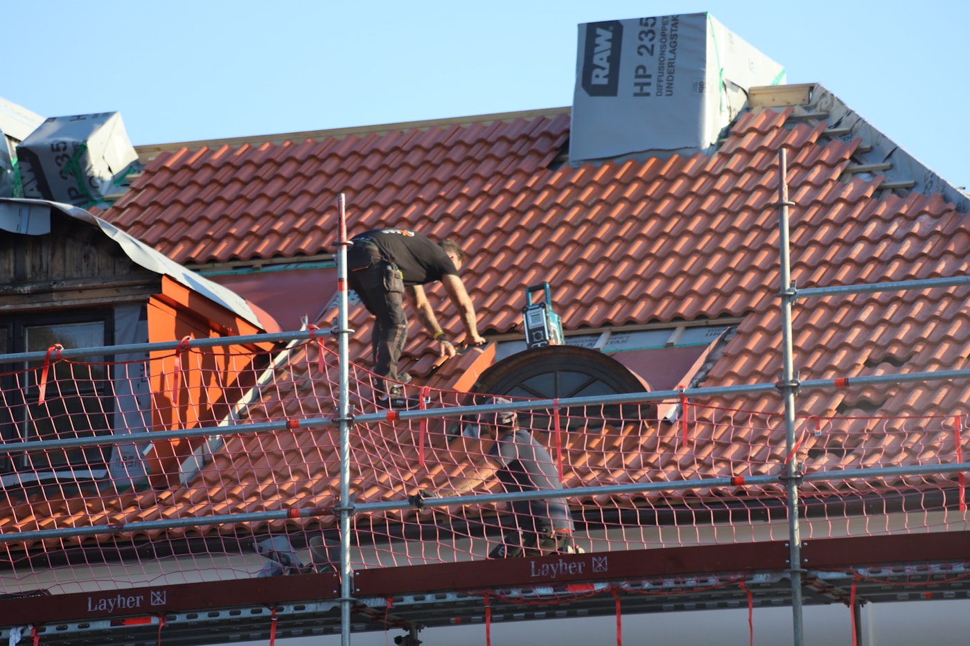 Roofer installing tiles on a house
